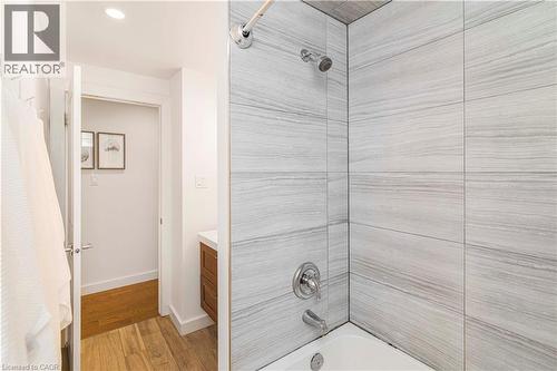 Bathtub with chrome fixtures and light-toned, wood-grain tile surround - 39 Forestgate Drive, Hamilton, ON 