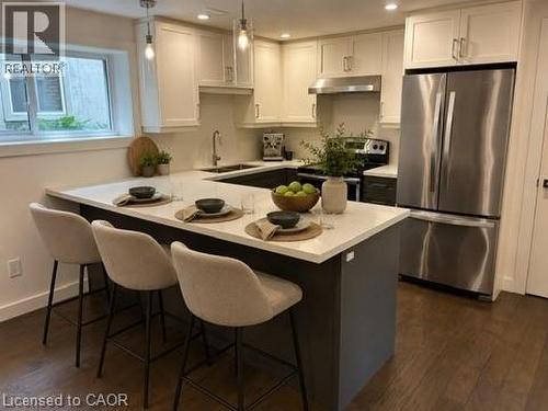 Virtually Staged Lower Unit. Kitchen featuring a U-shaped island with a white countertop, two-tone cabinetry, stainless steel appliances, and recessed lighting - 39 Forestgate Drive, Hamilton, ON 