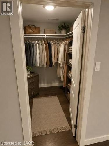 Virtually Staged Lower Unit. Walk-in closet with dark wood-finish flooring, white built-in shelving, and recessed lighting - 39 Forestgate Drive, Hamilton, ON 