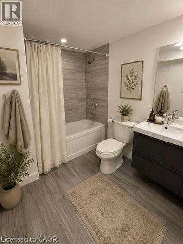 Virtually Staged Lower Unit. Full bathroom featuring a white tub with shower, gray wood-finish flooring, and a dark vanity with a white countertop - 39 Forestgate Drive, Hamilton, ON 