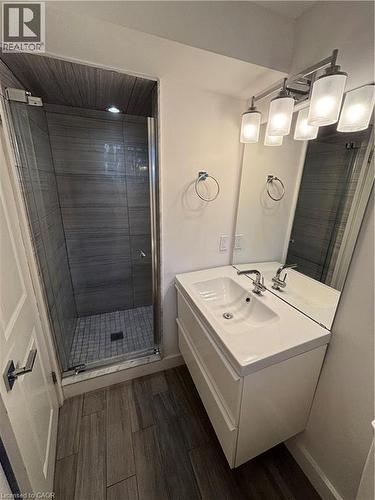Bathroom featuring a floating vanity with an integrated sink, a frameless mirror, and a five-light fixture - 39 Forestgate Drive, Hamilton, ON 