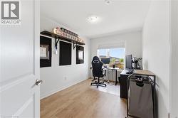 Well-lit room featuring light wood-finish flooring, white baseboards, and a single window with white trim - 