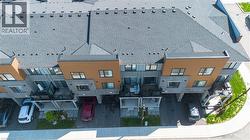 Modern multi-level townhome featuring a dark gray shingle roof, contrasting tan and gray facade, individual covered parking, and private balconies - 