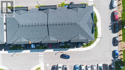 Multi-unit building featuring dark shingle roofing, multiple gables, individual covered parking, and an asphalt parking lot with painted white crosswalks - 