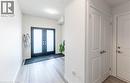 Entryway featuring wood-finish flooring, a double-door entry with frosted glass panels, white painted walls, and a flush-mount ceiling light - 92 Dryden Lane, Hamilton, ON 