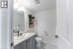Bathroom featuring a single vanity with wood-finish cabinetry, a white oval sink, and a large wall mirror - 