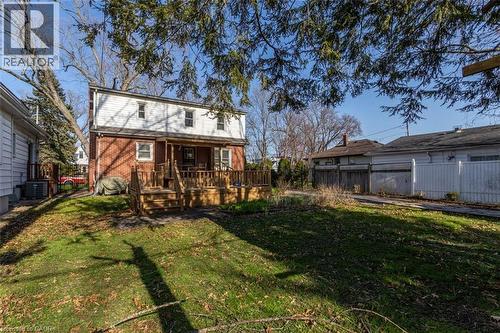 Spacious backyard featuring a multi-level wood deck, brick exterior, white siding, and mature trees - 17 Thorndale Street N, Hamilton, ON 