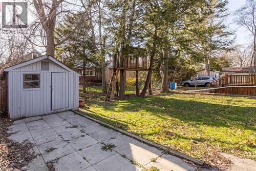 Spacious backyard featuring a storage shed, concrete patio area, and mature trees - 17 Thorndale Street N, Hamilton, ON 