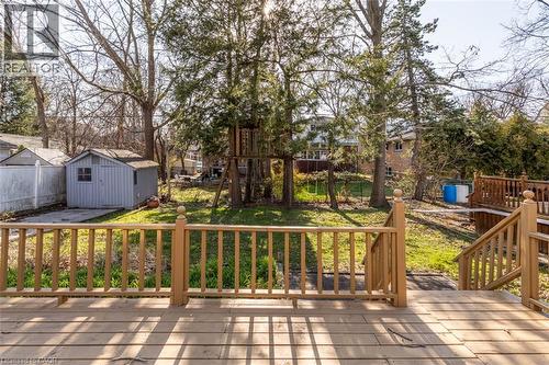Spacious backyard featuring a multi-level wood deck with baluster railings, a storage shed on a concrete pad, and mature trees providing natural screening - 17 Thorndale Street N, Hamilton, ON 
