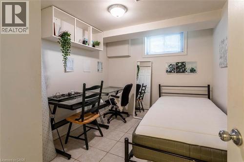Room featuring tiled flooring, a built-in wall shelf, recessed window with blinds, and white painted walls - 17 Thorndale Street N, Hamilton, ON 