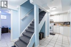 Stairwell with carpeted treads and white handrail leading to an upper level - 