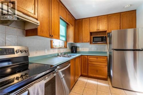 Kitchen featuring warm wood cabinetry, light-toned tile flooring, stainless steel appliances, and a built-in microwave - 17 Thorndale Street N, Hamilton, ON 