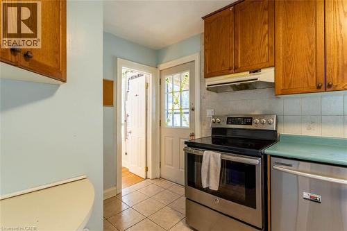 Kitchen featuring stainless steel range, stainless steel dishwasher, wood-finish cabinetry, tile flooring, and a glass-paned exterior door - 17 Thorndale Street N, Hamilton, ON 