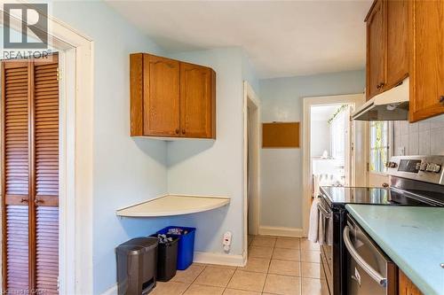 Kitchen featuring a stainless steel range with a black ceramic cooktop, a coordinating exhaust hood, wood cabinetry, and a tile backsplash - 17 Thorndale Street N, Hamilton, ON 