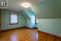 Room featuring wood-finish flooring, two windows with wood trim, and a ceiling-mounted light fixture - 