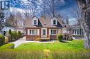 Brick residence featuring a gabled roofline with two dormer windows, a front wooden deck, and a manicured front lawn - 17 Thorndale Street N, Hamilton, ON 