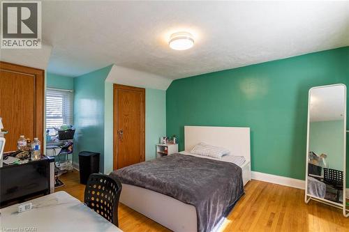 Hardwood flooring throughout featuring a window with blinds, two paneled wooden doors, and a flush mount ceiling light fixture - 17 Thorndale Street N, Hamilton, ON 