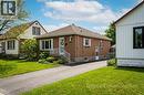 Brick exterior residence featuring a front entrance with white railings, a paved driveway, and established landscaping - 73 West 1St Street, Hamilton, ON 