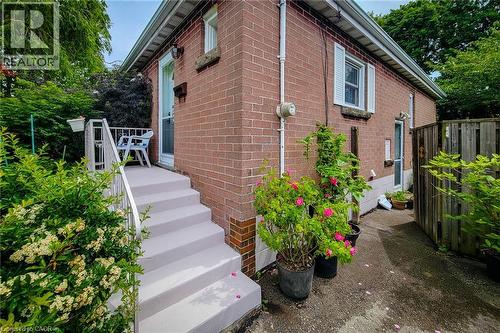 Brick exterior with white window shutters and a white-painted porch featuring a handrail - 73 West 1St Street, Hamilton, ON 