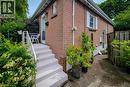 Brick exterior with white window shutters and a white-painted porch featuring a handrail. Privacy wooden fence build in 2022. - 73 West 1St Street, Hamilton, ON 