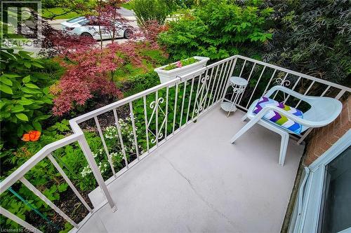 Balcony featuring a painted concrete surface, white metal railing with decorative scrollwork, and an exterior window - 73 West 1St Street, Hamilton, ON 