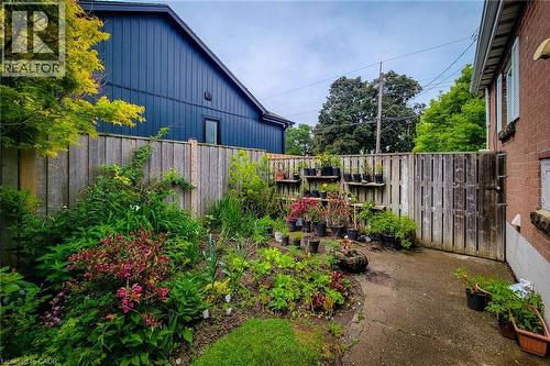 Fenced backyard featuring mature plantings, a concrete patio, and a privacy fence with a gate - 73 West 1St Street, Hamilton, ON 