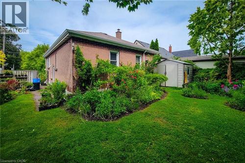 Expansive green lawn bordering a brick exterior with white trim - 73 West 1St Street, Hamilton, ON 