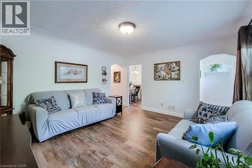 Spacious living area featuring wood-finish flooring, white painted walls, and a ceiling-mounted light fixture - 73 West 1St Street, Hamilton, ON 