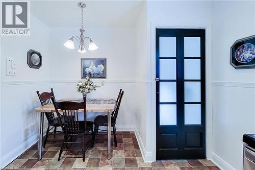 Compact dining area featuring a paneled wainscoting accent, a satin nickel chandelier, and multi-toned tile flooring - 73 West 1St Street, Hamilton, ON 