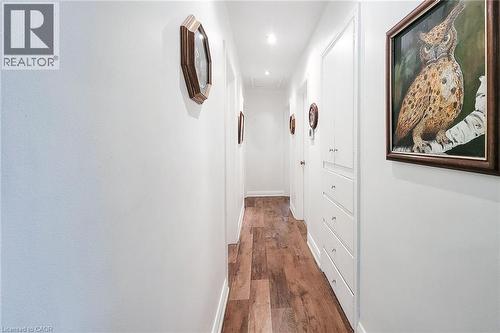 Hallway featuring wood-finish flooring, white walls, recessed lighting, and built-in white cabinetry with drawers and doors - 73 West 1St Street, Hamilton, ON 