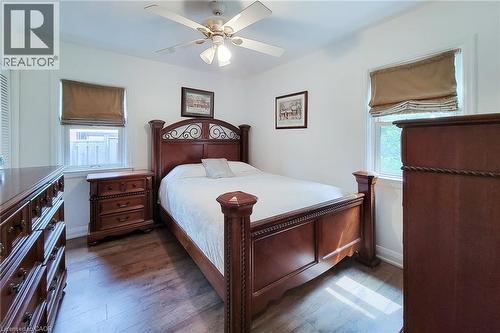 Bright room featuring two windows with privacy blinds, wood-finish flooring, and a ceiling fan with integrated lighting - 73 West 1St Street, Hamilton, ON 