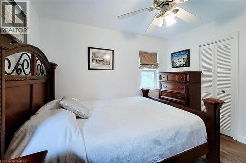 Bright bedroom with wood-finish flooring, a ceiling fan, and louvered bi-fold closet doors - 73 West 1St Street, Hamilton, ON 