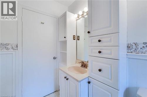 White vanity with an integrated sink and brushed nickel faucet, flanked by tall white cabinetry and open shelving - 73 West 1St Street, Hamilton, ON 