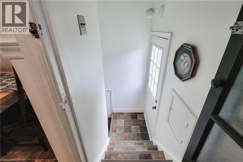Stairwell entry featuring multi-toned wood-finish steps and an exterior door with integrated window panels - 73 West 1St Street, Hamilton, ON 