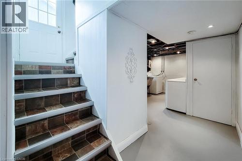 Staircase with multi-tone tile treads and white risers, leading to a white paneled door with window panes - 73 West 1St Street, Hamilton, ON 