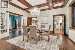 Dining area featuring dark wood-finish flooring, a coffered ceiling with recessed lighting, and a crystal chandelier - 