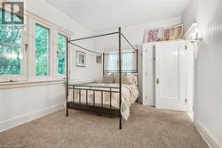 Carpeted room featuring a white paneled built-in wardrobe, three casement windows with white trim, and a wall-mounted sconce - 