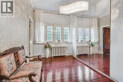 Hardwood flooring with a mirrored wall, intricate wallpaper, large multi-pane windows, and a crystal chandelier - 