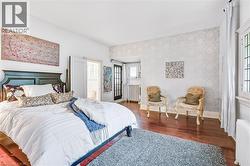 Spacious room featuring rich wood-finish flooring, patterned accent wall, and a large window with leaded glass details - 