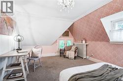 Attic space with sloped ceilings, crown molding, and patterned wallpaper - 