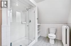 Glass-enclosed shower with white tiled surround and integrated shelving - 