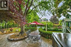 Expansive backyard featuring a patterned concrete patio, mature trees, manicured hedges, and a visible inground pool - 