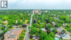 Aerial perspective of a verdant residential area featuring mature tree canopies, traditional architecture, and a central thoroughfare - 