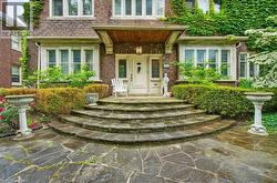 Brick exterior featuring stone steps, a covered entryway with a wood-paneled ceiling, and a prominent front door with sidelights - 
