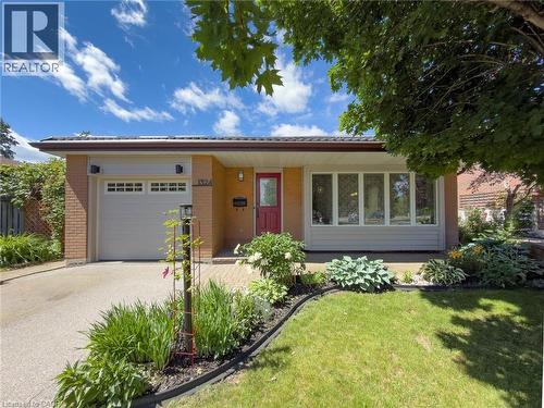 Brick exterior with an attached garage, featuring a red entry door and a large picture window - 1324 Bodley Road, Mississauga, ON 