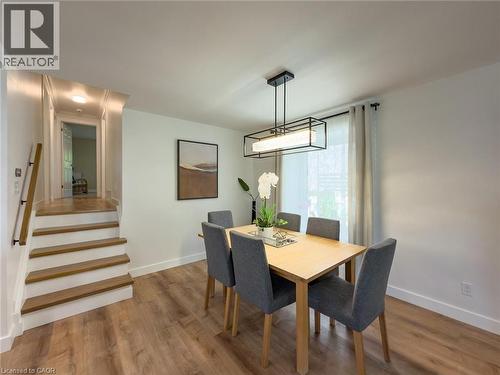 Dining area featuring wood-finish flooring, a rectangular light wood table, and a linear chandelier with a black frame - 1324 Bodley Road, Mississauga, ON 