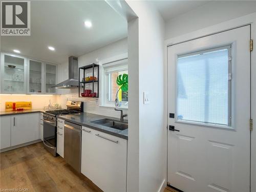 Modern kitchen featuring stainless steel appliances, grey countertops, white cabinetry, and wood-finish flooring - 1324 Bodley Road, Mississauga, ON 
