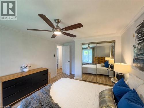 Room featuring wood-finish flooring, a ceiling fan with integrated lighting, crown molding, and mirrored closet doors - 1324 Bodley Road, Mississauga, ON 