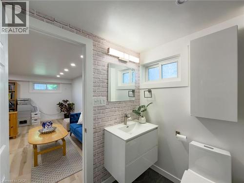 Contemporary bathroom featuring a white vanity with integrated sink, a rectangular mirror, and a frosted window - 1324 Bodley Road, Mississauga, ON 
