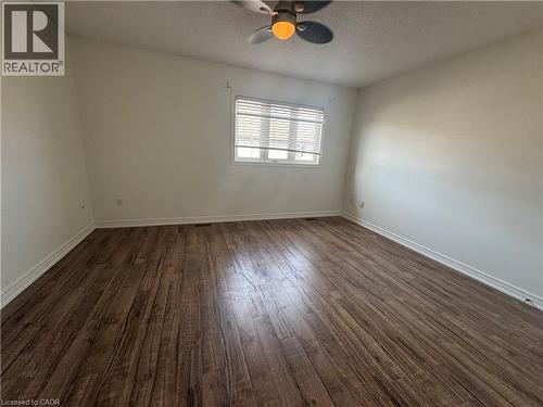 Spacious room featuring wood-finish flooring, white baseboards, and a window with blinds - 690 Summers Common, Burlington, ON - Indoor Photo Showing Other Room